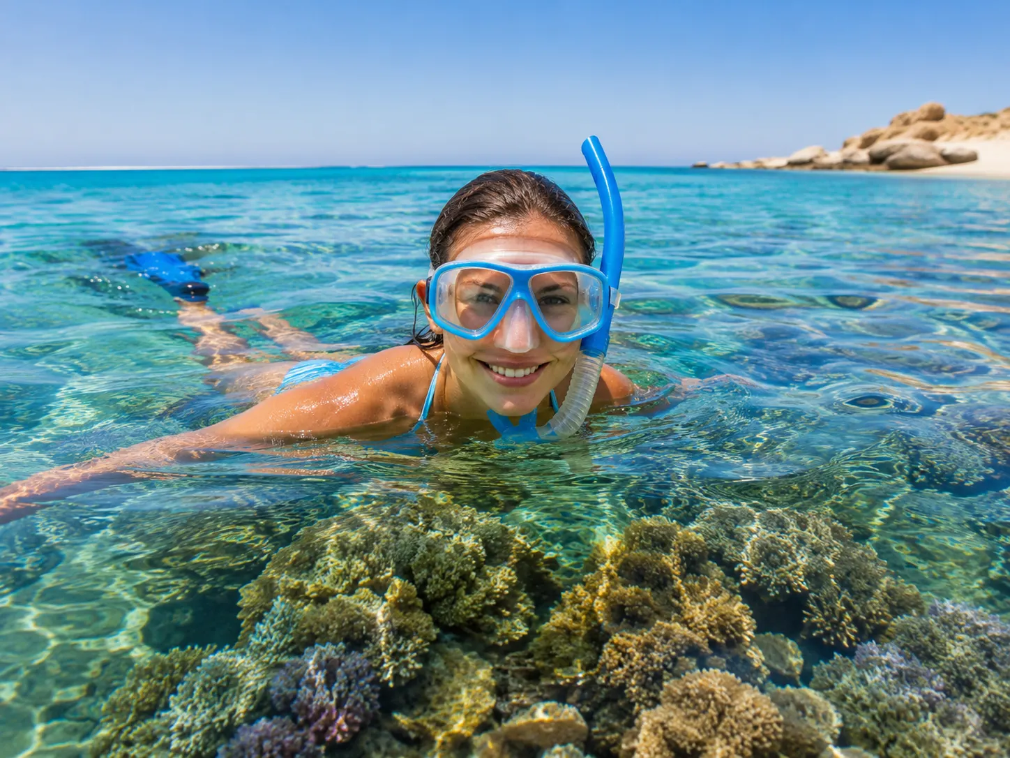 Femme souriante avec masque de snorkeling au-dessus d'un récif à Hurghada